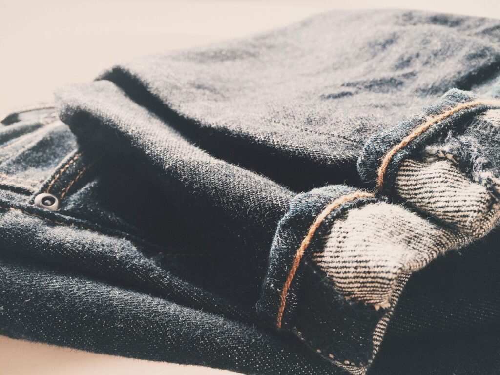 Detailed view of folded denim jeans in soft, warm lighting.