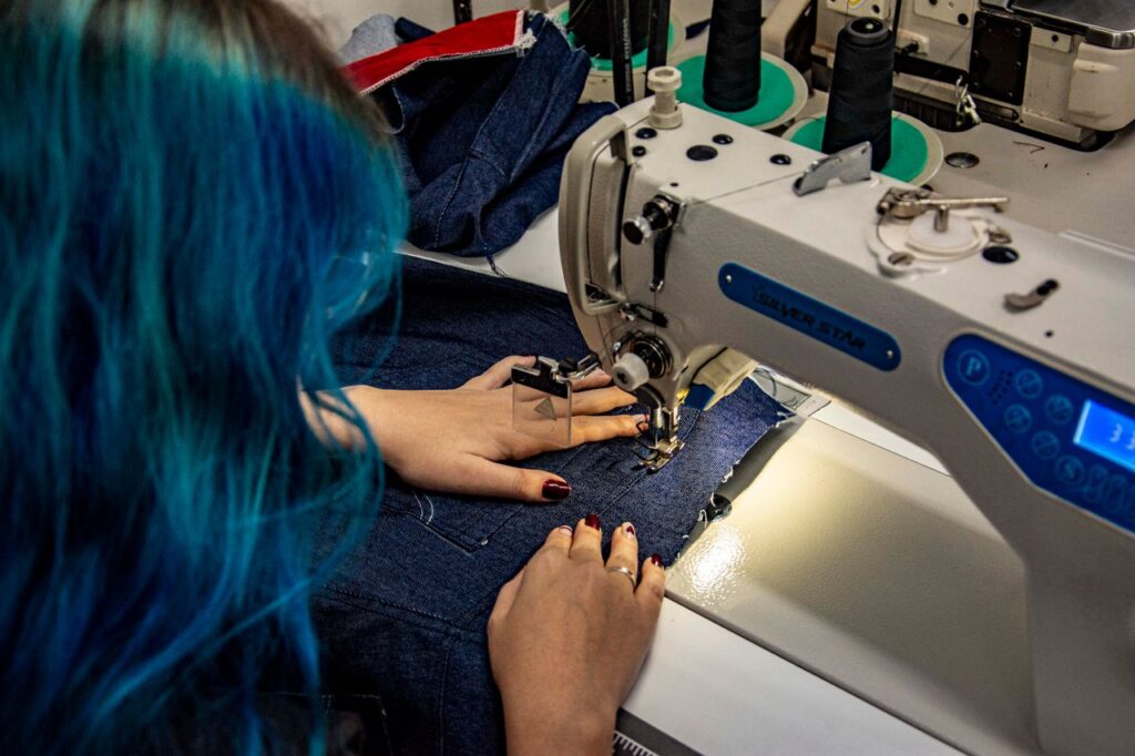 Hands sewing denim on a machine in Apucarana, Brazil. Detailed shot of skilled textile craftsmanship.